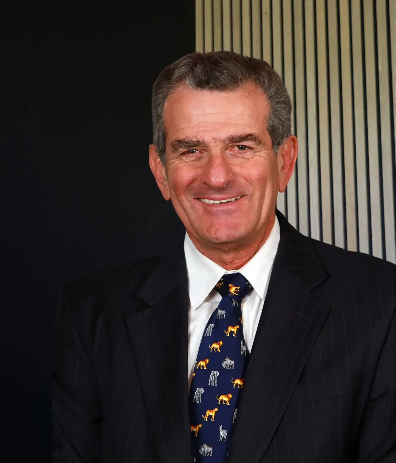 Smiling man in suit with animal print tie.